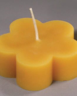 A yellow candle with a Floating Blossom - White beeswax on it.