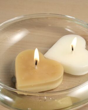 Two heart-shaped candles in a glass bowl.