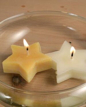 Two lit star-shaped candles in a glass bowl.