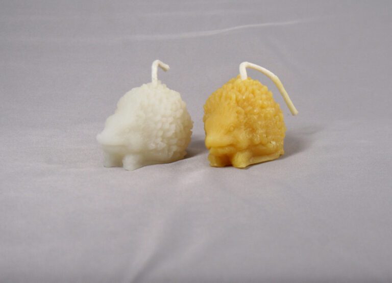 Two hedgehog shaped candles, one white, one yellow.