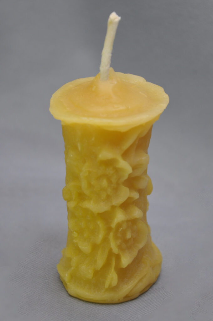 Yellow floral candle with white wick.