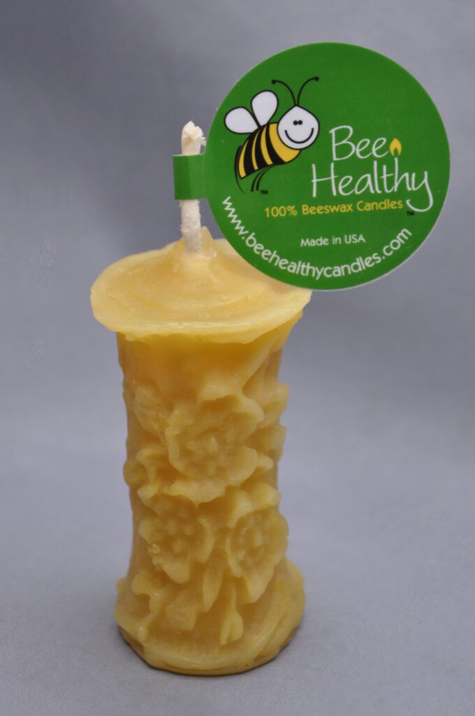 Yellow beeswax candle with floral design.