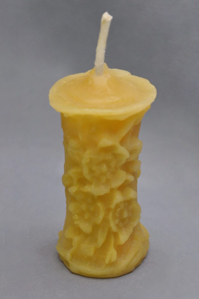 Yellow floral beeswax candle with wick.