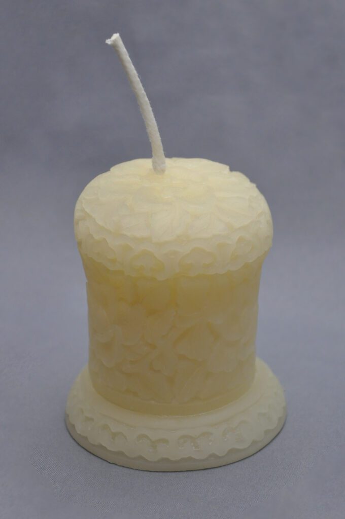 Ornate white pillar candle with wick.