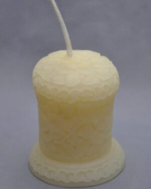 Ornate white pillar candle with wick.